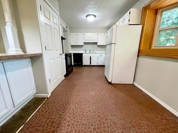 Jeffersonville house for rent - A kitchen with white cabinets and a black fridge.