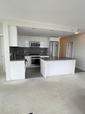 Burnaby apartment for rent - A kitchen with white cabinets and a black countertop.