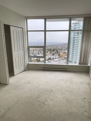 Burnaby apartment for rent - A room with a large window overlooking a cityscape.