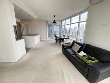 Burnaby apartment for rent - A black couch with a green pillow is in the middle of a living room.