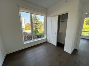 Vancouver apartment for rent - A room with a large window and a view of a garden and a building outside.