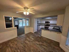 Harrah house for rent - A room with a ceiling fan and a kitchen area in the background.