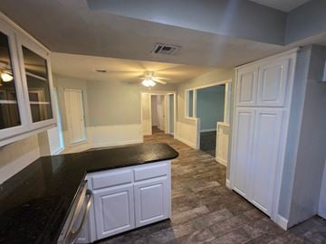 Harrah house for rent - A kitchen with a black counter top and white cabinets.