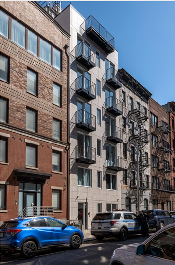 New York apartment for rent - A blue car is parked on the street in front of a building.