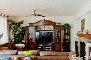 Phoenix house for rent - A living room with a brown leather couch and a wooden entertainment center.