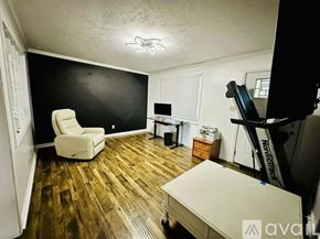 Henderson house for rent - A room with a white chair and a wooden floor.