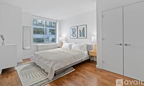 New York apartment for rent - A bedroom with a bed, a nightstand, and a window with a view of a building outside.