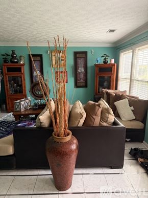 Lawrenceville house for rent - A brown vase with tall thin sticks in it sits on a table.