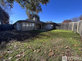 Plano house for rent - A house with a fence and trees in the background.