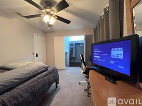 Plano house for rent - A bedroom with a bed, a television, and a ceiling fan.