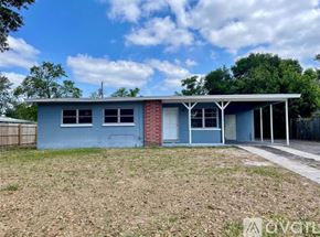 Sanford house for rent - A blue house with a red brick chimney is surrounded by a grassy area.