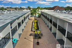 Kissimmee apartment for rent - A sunny day at the rooftop of a building with a long walkway and potted plants.