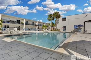 Kissimmee apartment for rent - A large swimming pool surrounded by a tiled patio and a building with balconies.