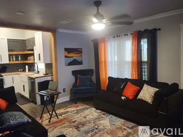 Atlanta house for rent - A living room with a black couch and orange curtains.
