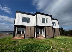 Canso apartment for rent - Two houses with white and brown siding are situated on a grassy area.