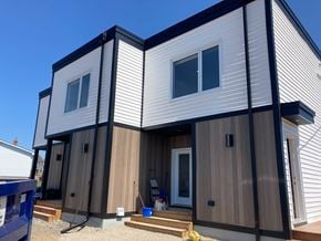 Canso apartment for rent - A modern house with a white and dark exterior and a wooden front door.
