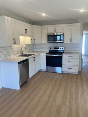 Canso apartment for rent - A kitchen with white cabinets and a black stove top oven.