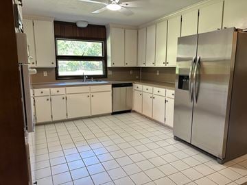 Statesboro house for rent - A kitchen with white cabinets and a stainless steel refrigerator.
