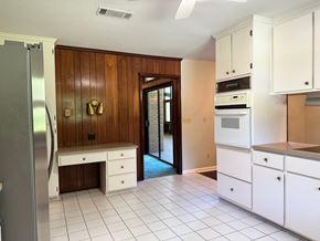 Statesboro house for rent - A kitchen with white cabinets and a wooden wall.