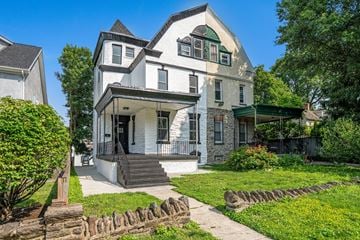 Philadelphia house for rent - A white house with a green roof and a black door.