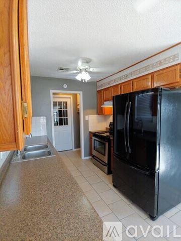 Lawton house for rent - A kitchen with a black refrigerator and wooden cabinets.