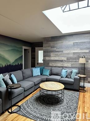 Ellsworth apartment for rent - A grey couch with blue pillows sits in front of a grey wall with a mountain mural.