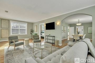 Savannah house for rent - A living room with a grey couch, a glass coffee table, and a television mounted on the wall.