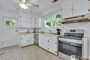 Savannah house for rent - A kitchen with white cabinets and appliances, a ceiling fan, and a window.
