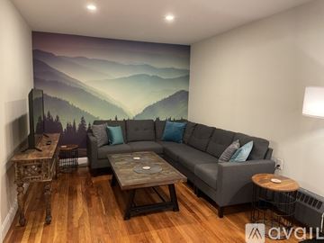 Ellsworth apartment for rent - A living room with a grey couch and a mountain mural on the wall.