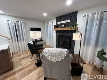 Colorado Springs house for rent - A cozy living room with a fireplace and a chair with a white shawl draped over it.