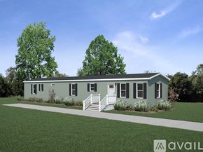 Alpine house for rent - A house with a greenish exterior and a white door is surrounded by greenery.