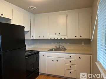 Sea Tac apartment for rent - A kitchen with white cabinets and a black refrigerator.