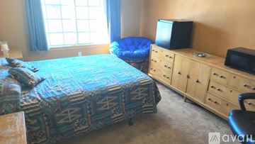 Victorville house for rent - A living room with a couch, a painting, and a table with a vase of flowers on it.