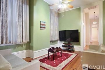 New Orleans house for rent - A living room with a television and a red rug.