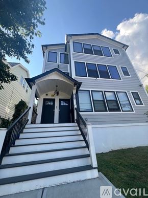 Newark apartment for rent - A two-story house with a black front door and stairs leading to the entrance.