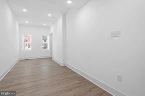 Baltimore house for rent - A long, empty hallway with wood floors and white walls.