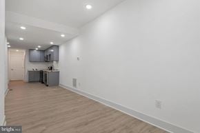 Baltimore house for rent - A brightly lit empty room with wooden flooring and white walls.