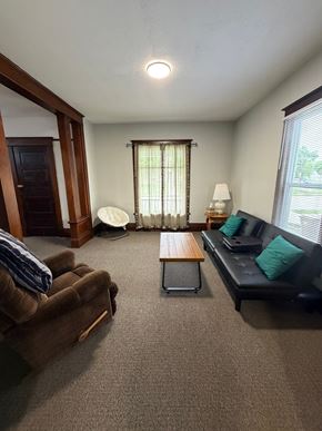 Grinnell apartment for rent - A living room with a brown couch, a wooden table, and a lamp.