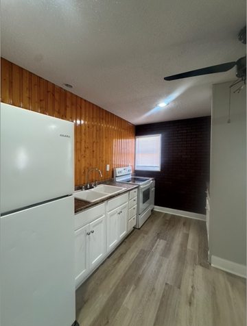Trumann house for rent - A kitchen with white appliances and wooden walls.