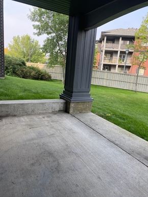 Edmonton apartment for rent - A concrete porch with a grey pillar and a green lawn.