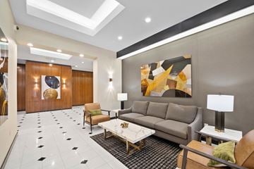 New York apartment for rent - A modern living room with a grey sofa, a coffee table, and a large abstract painting on the wall.