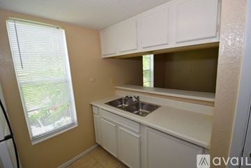 Corpus Christi apartment for rent - A kitchen with white cabinets and a window with blinds.