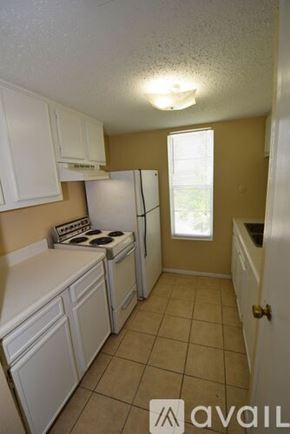 Corpus Christi apartment for rent - A kitchen with white cabinets and a stove top oven.