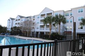 Charleston apartment for rent - A pool in front of a building with a black fence.