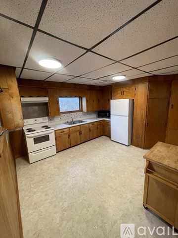 Watertown house for rent - A kitchen with wooden cabinets and a white refrigerator.