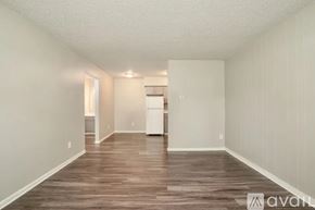 Longmont apartment for rent - A room with wooden flooring and white walls, with a kitchen area visible in the background.