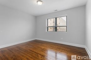 Chicago apartment for rent - A room with wooden flooring and a window showing a view of a building outside.