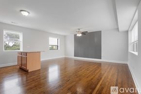 Chicago apartment for rent - A spacious room with wooden floors and a ceiling fan.