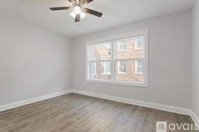 Chicago apartment for rent - A room with a ceiling fan and a window overlooking a brick building.