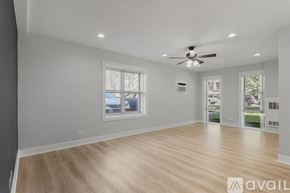 Chicago apartment for rent - A spacious room with a ceiling fan and wooden flooring.